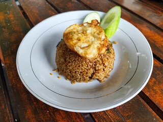 Delicious fried rice with vegetables and egg served on a wooden table.
