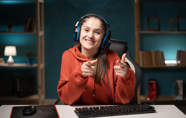 flirty funny woman gamer play game. Female gaming player wearing headset winking pointing with...