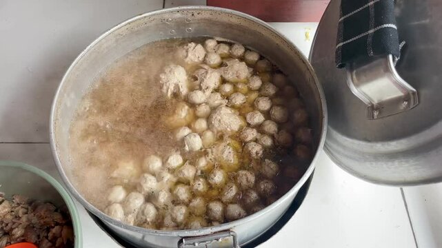 Boiling meatballs in an open hot pot and the boiling water erupts with hot steam. the process of boiling round meatballs