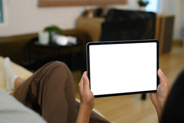 Closeup of hands holding digital tablet with a blank display lying on sofa