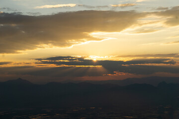 breathtaking sunset over mountains, with rays of light breaking through clouds, creating serene and tranquil atmosphere. sky is painted in warm hues of orange and yellow