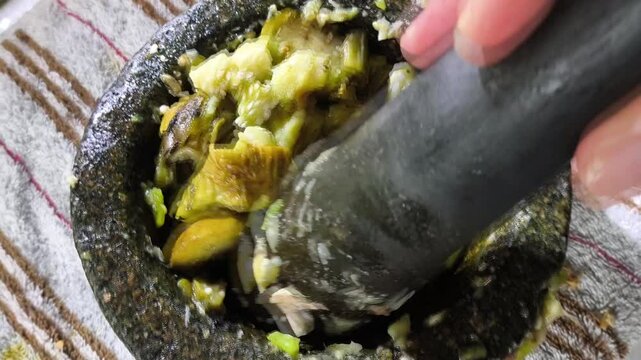 Pounding chopped eggplant in mortar, in door  Chiangmai  Thailand.