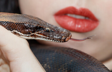 A woman is holding a snake with a red tongue