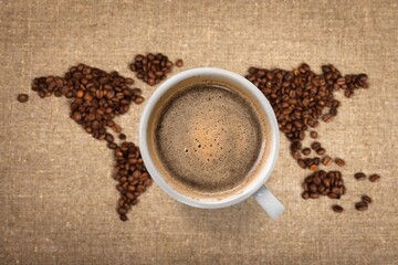 Cup of tasty hot coffee and coffee beans on desk