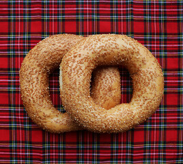 2 two round bagels with sesame seeds isolated on red tablecloth background. sweet circle donut.