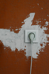 plaster covered gap for an electrical outlet in an orange concrete wall. Close up of a electrical...