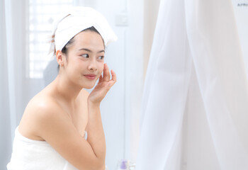 Asian young woman with towel wrapped on head and body applying makeup after shower, Morning beauty routine before work