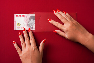 Lucky Indonesian chinese woman opening a red envelope gift, find large amount of money inside, one...