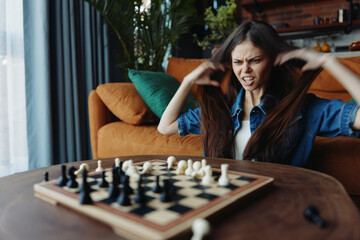 A woman deep in thought playing chess at a table in a cozy living room setting