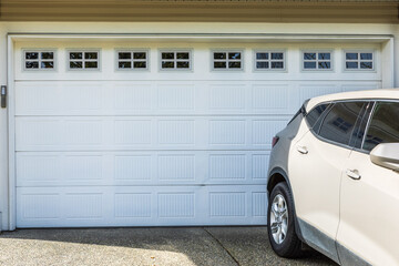 Gray Garage door with windows and a car parked in front drive way. Garage door in luxury house