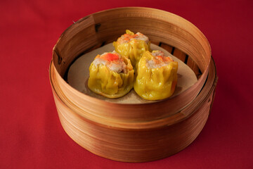 Steamed shumai dim sum on wooden plate isolated on red background. Steamed dumplings for Chinese New Year party.