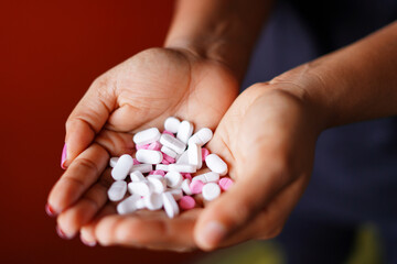 white and pink pills in hands image