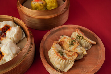 Fried kuotie dim sum on wooden plate isolated on red background. Steamed dumplings for Chinese New...