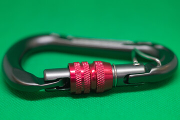 Metal carabiner for rock climbing on green background, isometric view