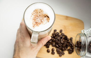 Cropped Hands Of Woman Holding Cappuccino Over White Background