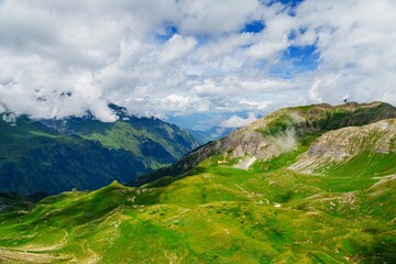 Fototapeta premium This stunning image showcases the majestic beauty of Kaprun, Austria, featuring lush green hills and towering mountains that create a breathtaking landscape, perfect for outdoor activities.