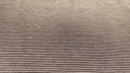 A textured cardboard surface with a rough and corrugated design in brown and gray, resembling an old paper wall or backdrop with subtle striped patterns