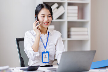 Asian woman entrepreneur busy with her work in the office. Young Asian woman work on desk laptop phone while planning sales, research or financial strategy in company
