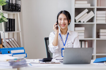 Asian woman entrepreneur busy with her work in the office. Young Asian woman work on desk laptop phone while planning sales, research or financial strategy in company
