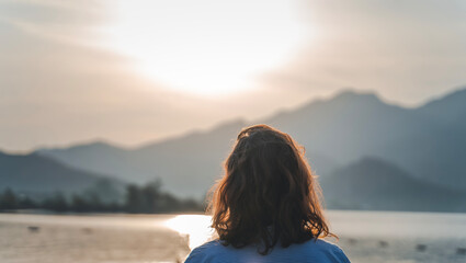 Woman standing with her back resting looking at the sea bay with mountains