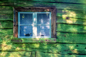 Window of a wooden cottage with green lichen on the wall © Lars Johansson