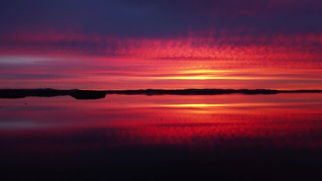 4K aerial of dead calm lake water reflecting the evening sunset like a mirror in Sweden
