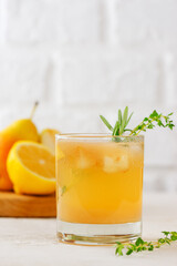 Cold pear cocktail, lemonade with lemon, rosemary, thyme and ice in a glass on a white background. Healthy drink, sugar and alcohol free. Vertical orientation.