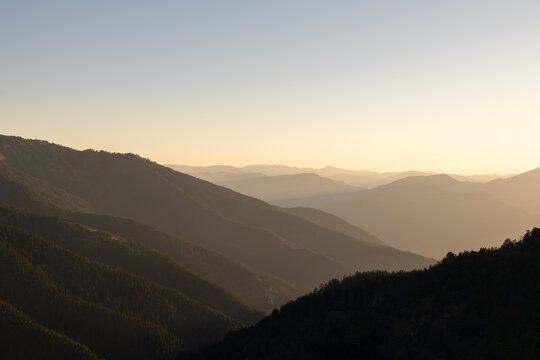 Landscape of the hazy mountains at sunset or sunrise. Layered hills