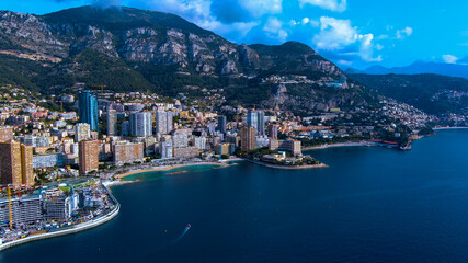 Naklejka premium Breathtaking aerial view of Monaco featuring its modern skyline, coastal beauty, and lush mountains. Perfect for travel, architecture, and luxury lifestyle visuals.