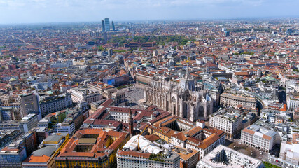 Fototapeta premium Breathtaking aerial view of Milan, Italy showcasing the iconic Duomo Cathedral surrounded by historic buildings and modern architecture. Perfect for travel, urban visuals, and cultural landmarks.