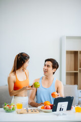 Fit couple preparing healthy food at home, featuring fresh fruits, salad, and wellness