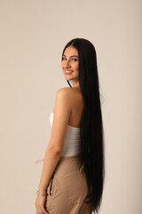 Vertical headshot of beautiful and happy woman with long dark hair looking at the camera. 