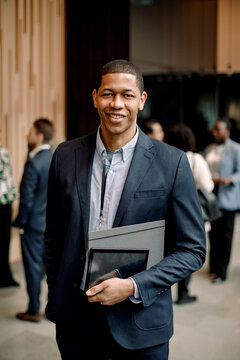 Portrait of smiling male entrepreneur holding digital tablet and folder while standing at convention center