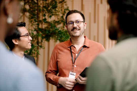 Smiling male entrepreneur discussing with delegates in seminar at convention center