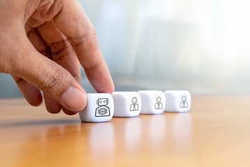 A hand is picking a cube with a robot icon next to three cubes with sad human icons. Artificial Intelligence affect human jobs concept.