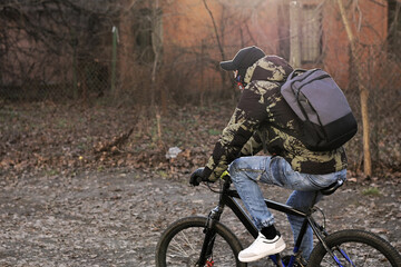 Fototapeta premium Person cycling through an autumnal setting, wearing a backpack and warm clothing