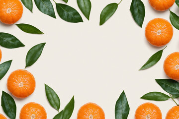 A flat lay composition of mandarin oranges and leaves on a light background, forming a border