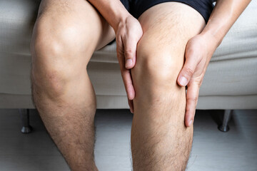 Man with knee pain, he puts his hand on his knee, pain point from osteoarthritis and...