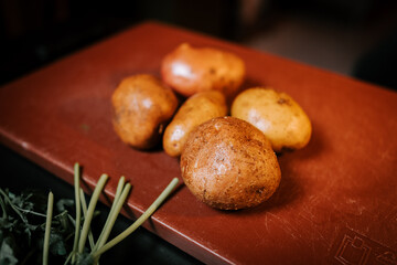 Freshly Harvested Ripe Potatoes Arranged on a Wooden Board in a Cozy Kitchen Ready for Cooking or Baking