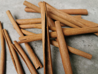 Fresh and raw Indonesian organic cinnamon sticks scattered on marble background