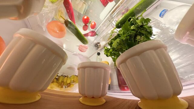 Rotating view from inside a refrigerator, shifting perspective from top to bottom to capture various foods including vegetables and containers. The dynamic angle provides a fresh look at the organized