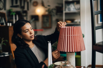Young female entrepreneur adjusting lamp shade while working at antique store