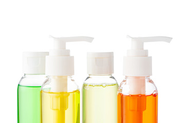 Various bottles with colored liquids and pumps arranged on white background
