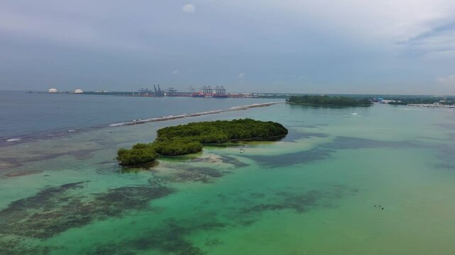 La Matica islet, impenetrable mangrove forest, Playa Boca Chica beach, Caucedo port in background, Santo Domingo in Dominican Republic. Aerial drone orbiting, sky for copy space