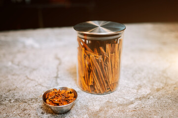 Cinnamon Sticks Arranged in a Glass Jar Alongside a Smaller Bowl of Loose Cinnamon Pieces on a...
