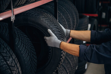 Close up view, taking the tire. Man worker is maintenance station with wheels