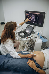 Monitor with graphical representation of scan. Pregnant woman undergoing ultrasound test