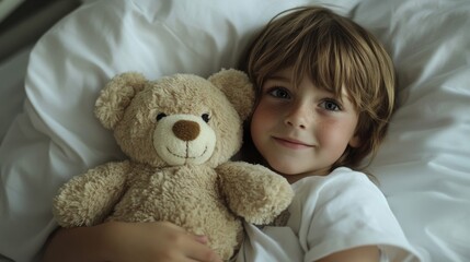 Young Boy Lying in Bed Holding a Teddy Bear