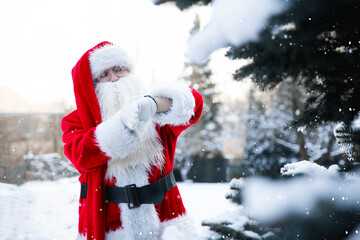 St. Nicholas with a watch in his hands is waiting for the New Year and Christmas against the background of the Christmas tree Santa Claus