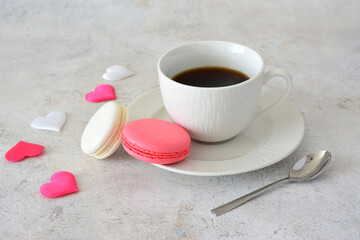 a cup of coffee and macaroons with some silk pink and white hearts